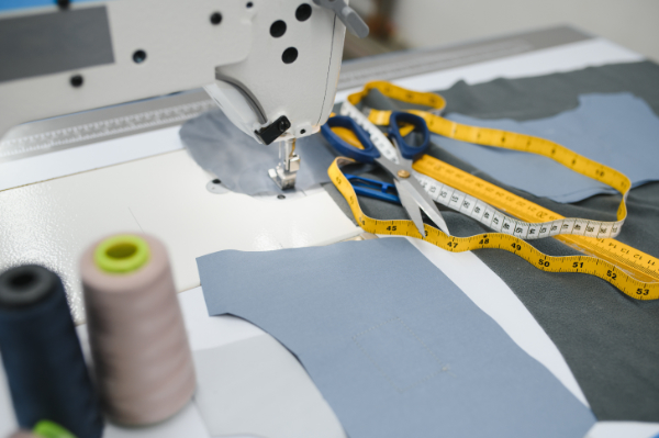 Composition of sewing thread, scissors and tape measure on a white table. Concept of a clothing designer